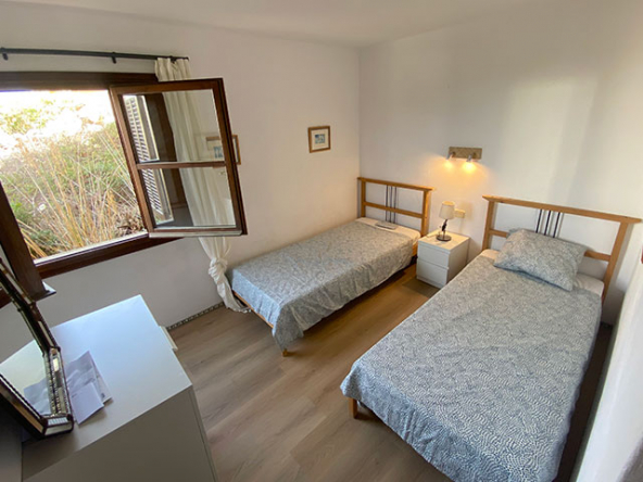 Dormitorio doble con estilo mediterráneo y carpintería de madera.