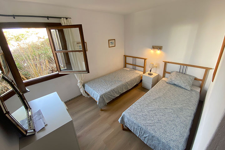 Dormitorio doble con estilo mediterráneo y carpintería de madera.